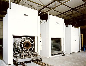 Hornos de cámara de calentamiento indirecto por medio de gas, provistos de puertas elevadoras eléctricas y con carretillas de plataforma automotoras, equipadas con dispositivos de rodillos para la fabricación de grandes motores eléctricos.